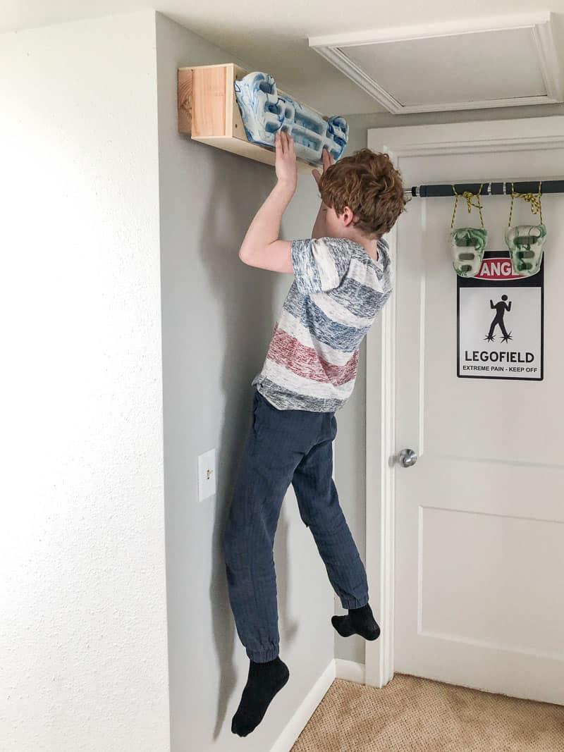 kid on hangboard mounted to wall