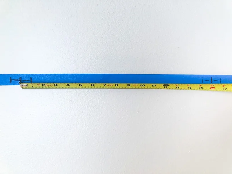 painter's tape on wall with markings for studs and tape measure showing 16" on center