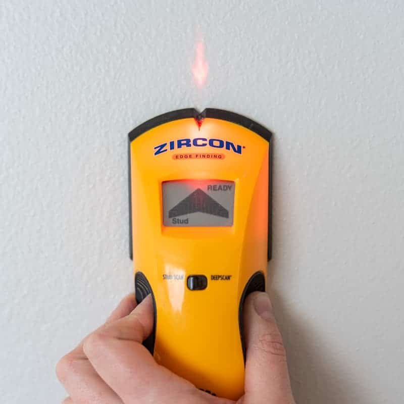 stud finder showing edge of a stud with a complete set of bars and a laser arrow on the wall