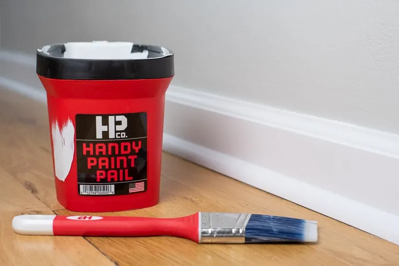 Handy Paint Pail and paint brush next to painted baseboards