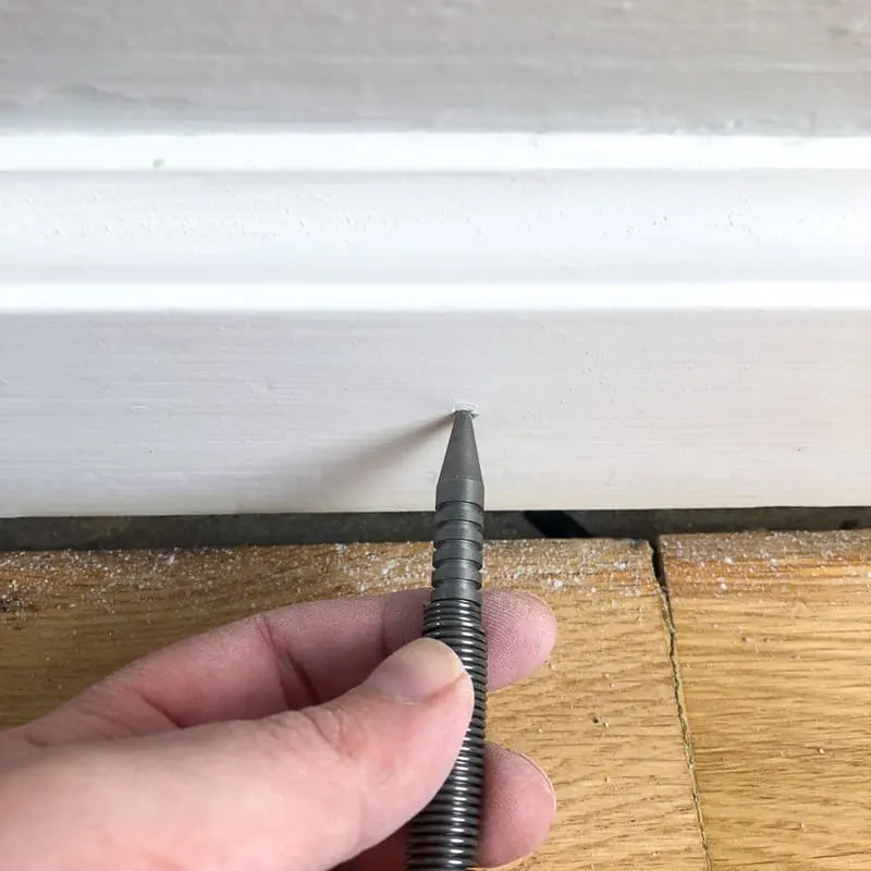 using spring loaded nail set to sink popped nails in baseboards
