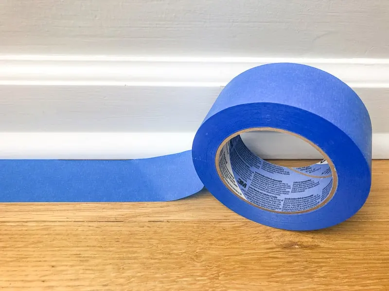 applying painter's tape to floor before painting baseboards