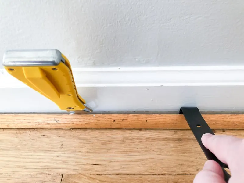 using putty knife and small pry bar to remove quarter round without damaging baseboards
