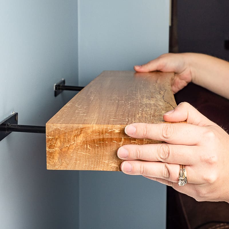 live edge floating shelf being installed on wall