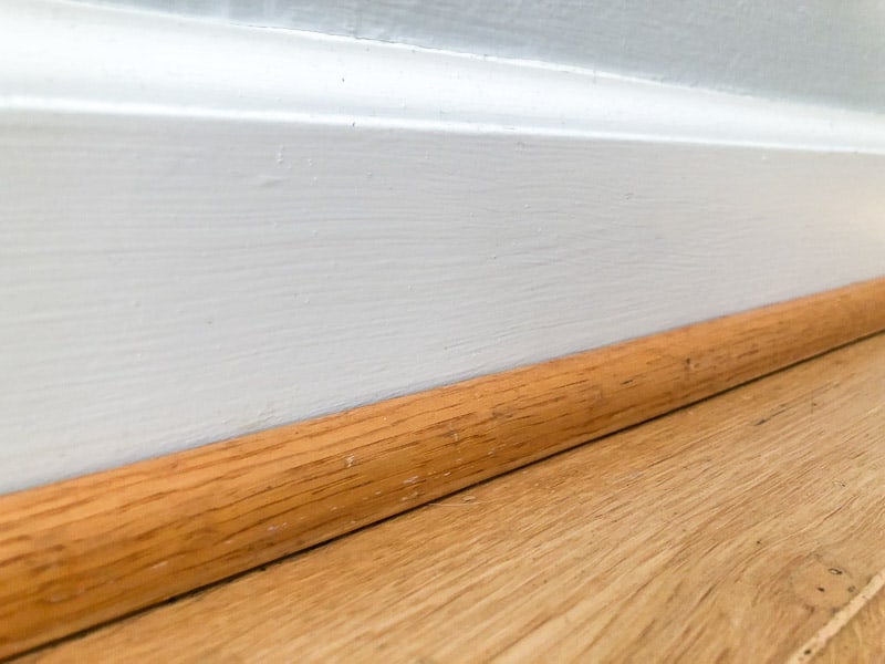 oak quarter round trim on white baseboards