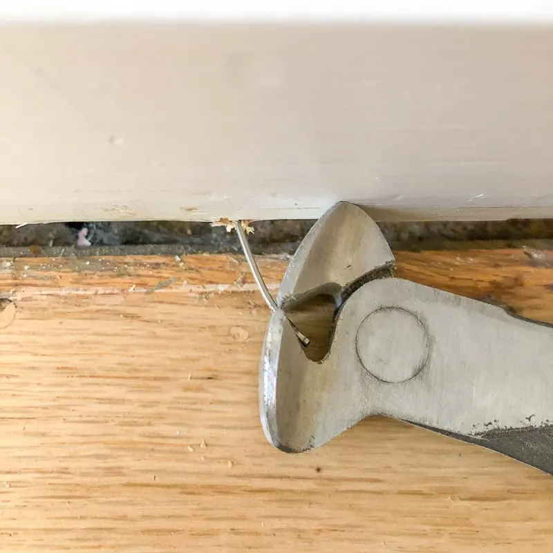 using a nail puller to remove nails from baseboards after quarter round trim is removed