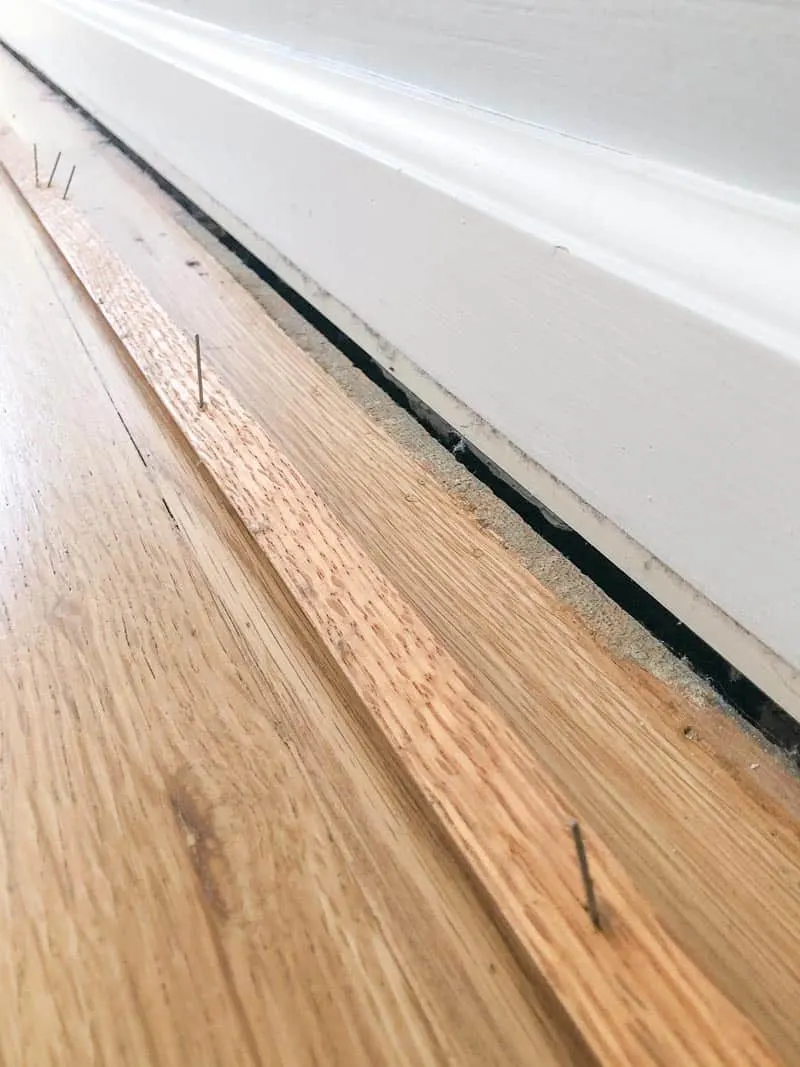 quarter round trim removed from baseboards, exposing gap between floor and wall