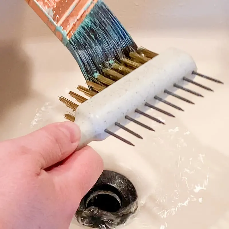using fine bristles from brush comb to remove dried paint from outside of paint brush