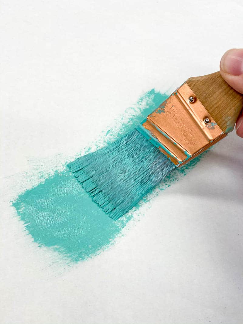 removing excess paint from brush with paper