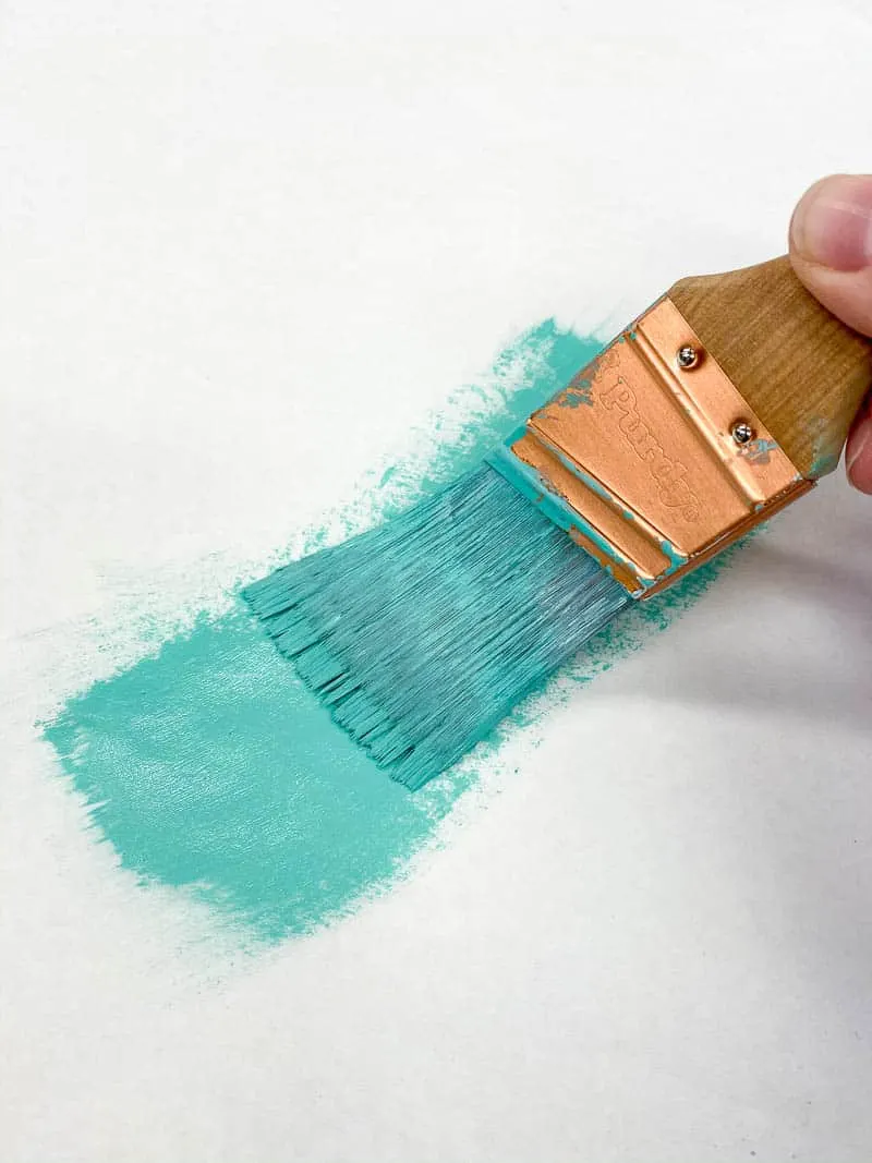 removing excess paint from brush with paper