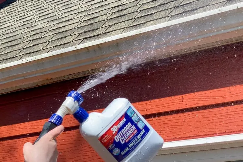 spraying cleaner on outside of gutters