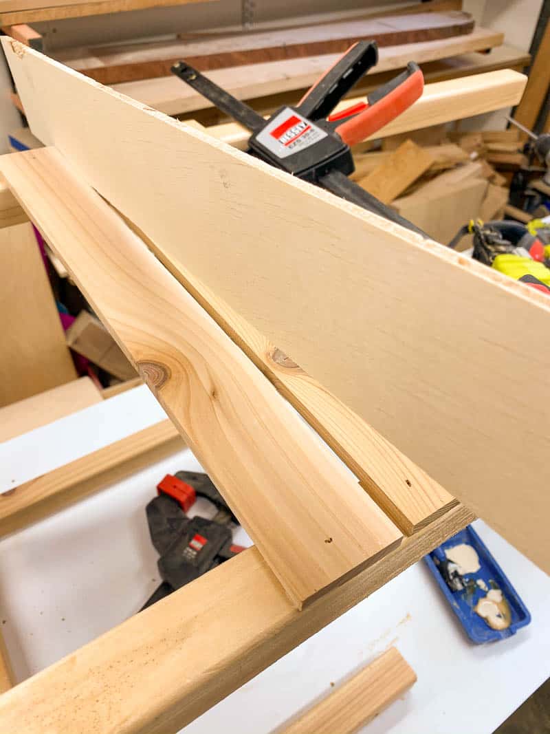 using a scrap of plywood as a spacer between the slats of a DIY planter box