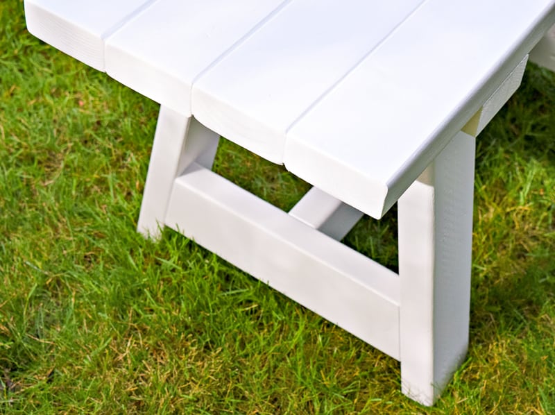 close up of white 2x4 bench on grass