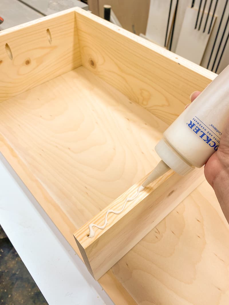 applying wood glue to Trofast shelf frame