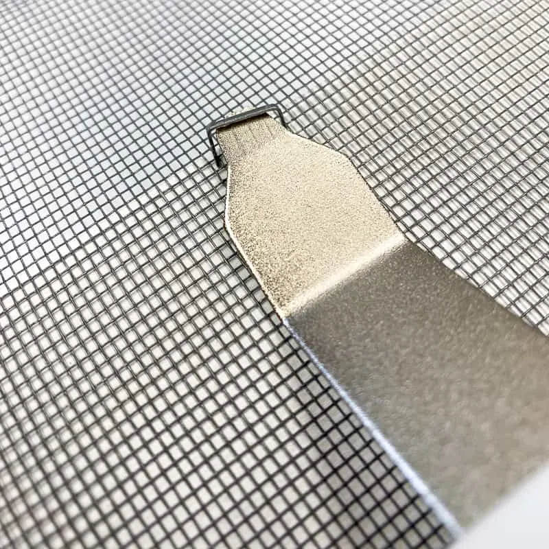removing a staple from the mesh screen on a DIY screen door