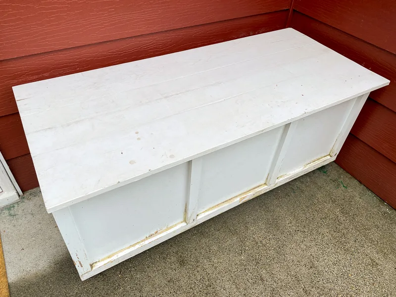 ruined white outdoor storage bench after years in the rain