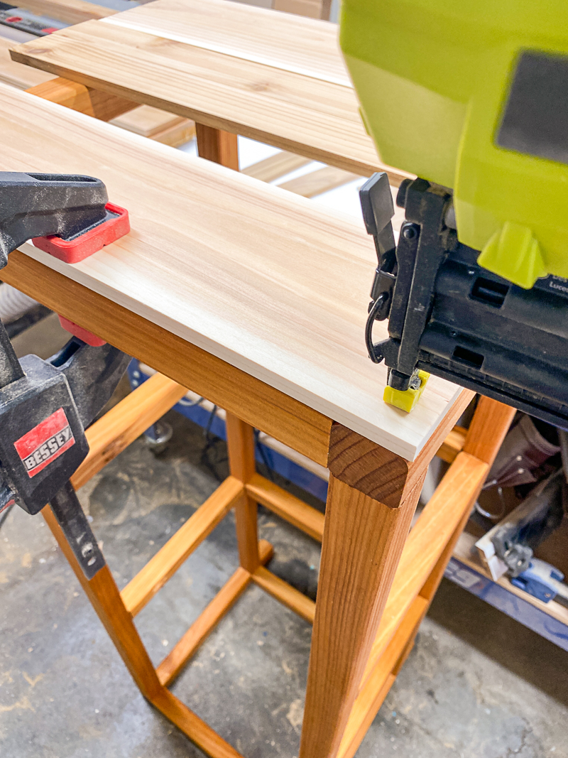 nailing first slat onto frame of DIY outdoor storage box