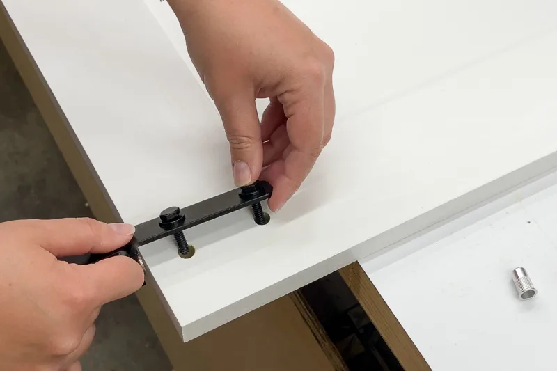 inserting folding barn door hardware into holes at top of cabinet door