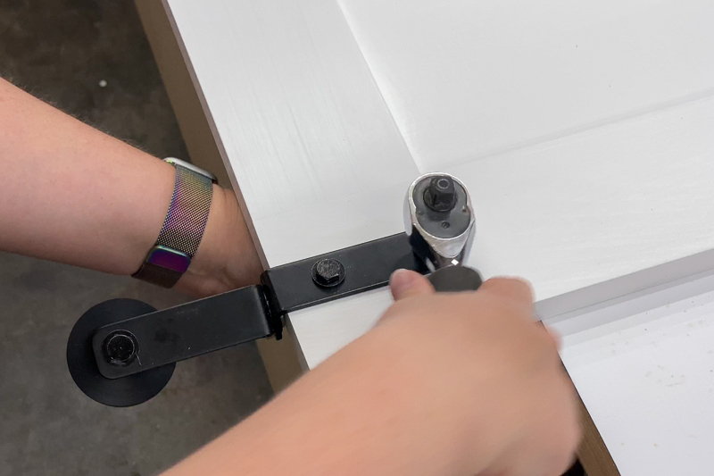 using socket wrench to tighten bolts on folding barn door hardware