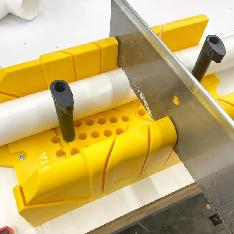 using a miter box to cut PVC pipe for a Nerf gun storage rack