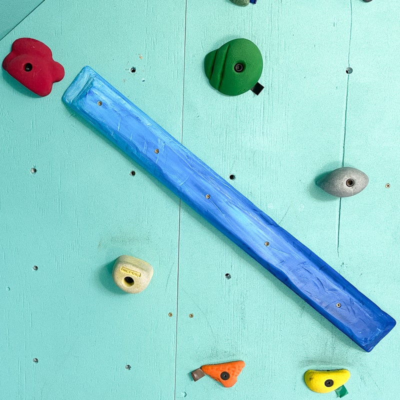 long blue wooden climbing hold on wall