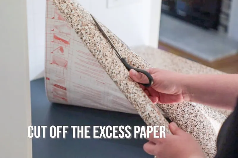 cutting contact paper to the size of the countertop with scissors