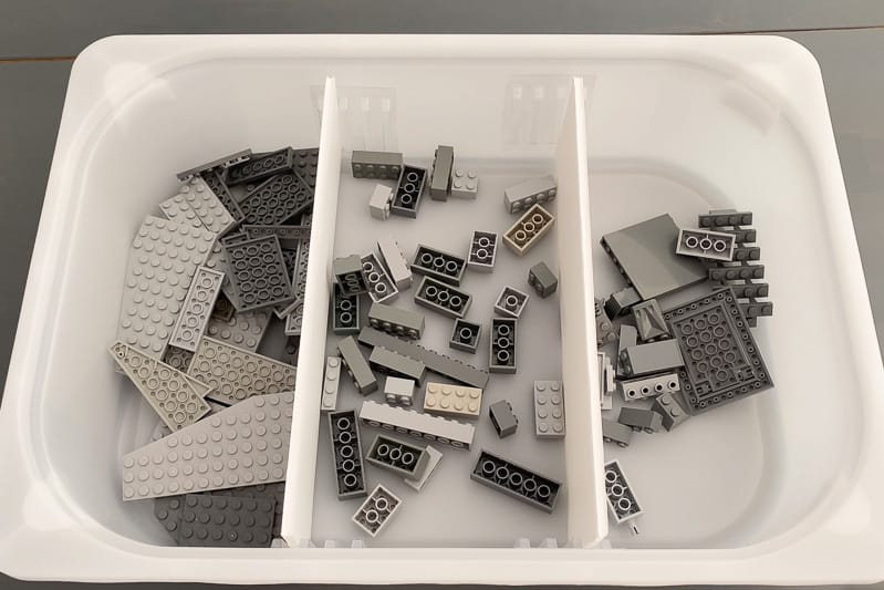 DIY drawer dividers in plastic bin with sorted gray Lego pieces