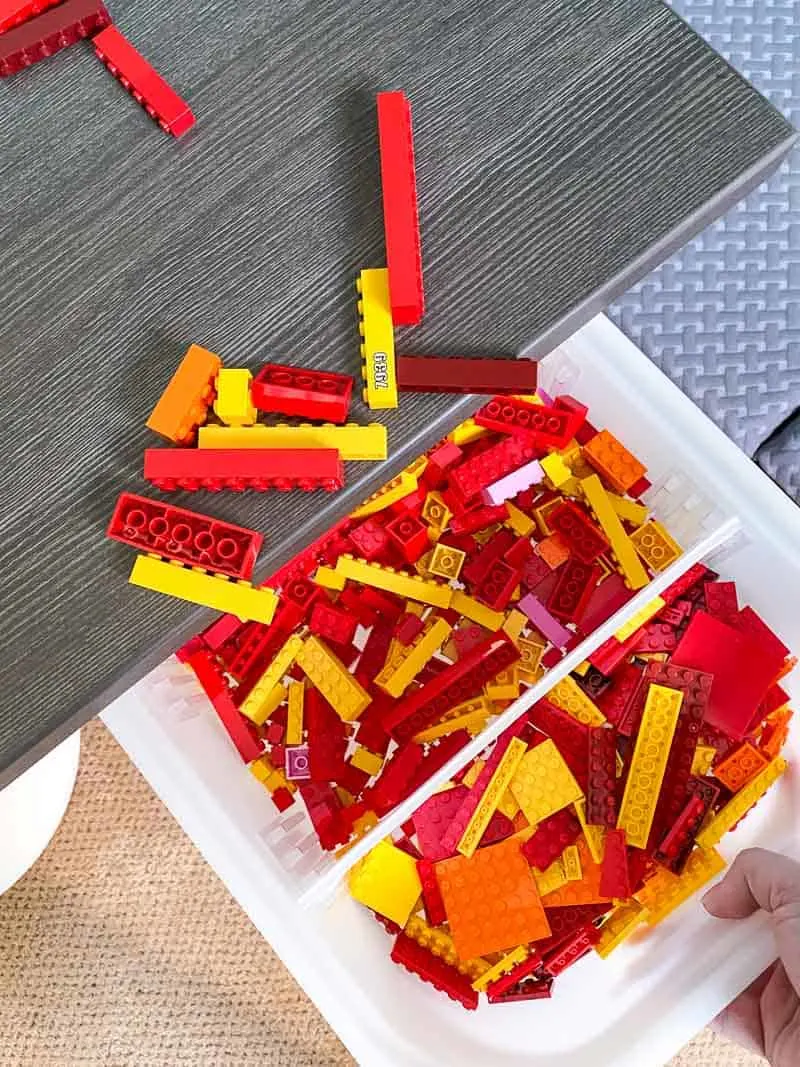 cleaning up Lego pieces by sliding them into a bin in the Lego desk