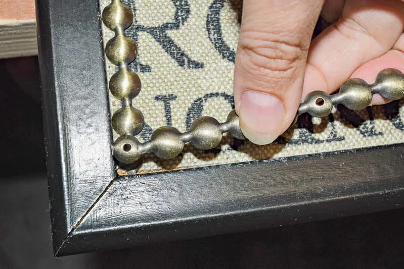 securing the corners of the nailhead trim on the DIY push pin travel map