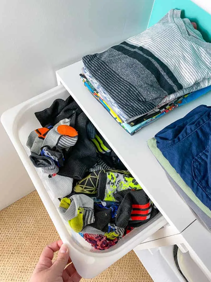 wall mount storage bins being used as a dresser with bins for socks and the top as a shelf