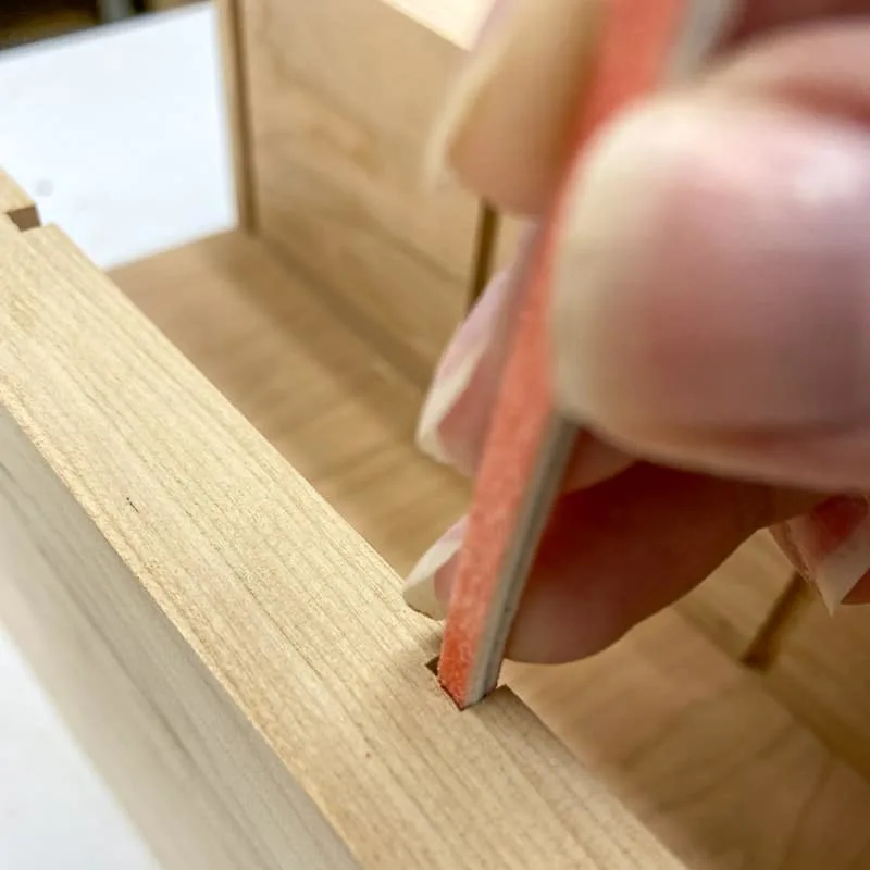 sanding the grooves in the laptop stand with sanding sticks