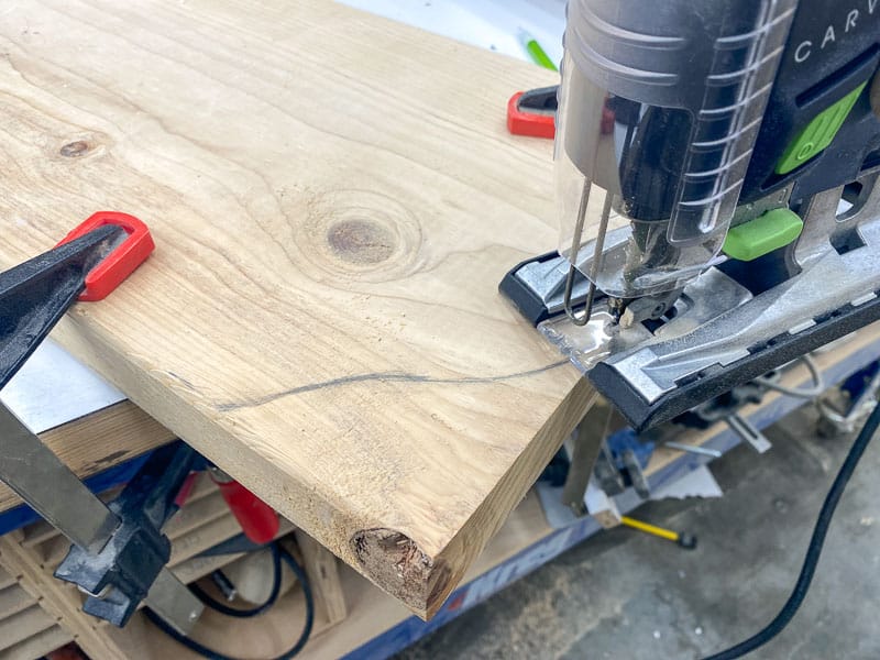 cutting off corner of scrap wood with a jigsaw to create a tombstone shape