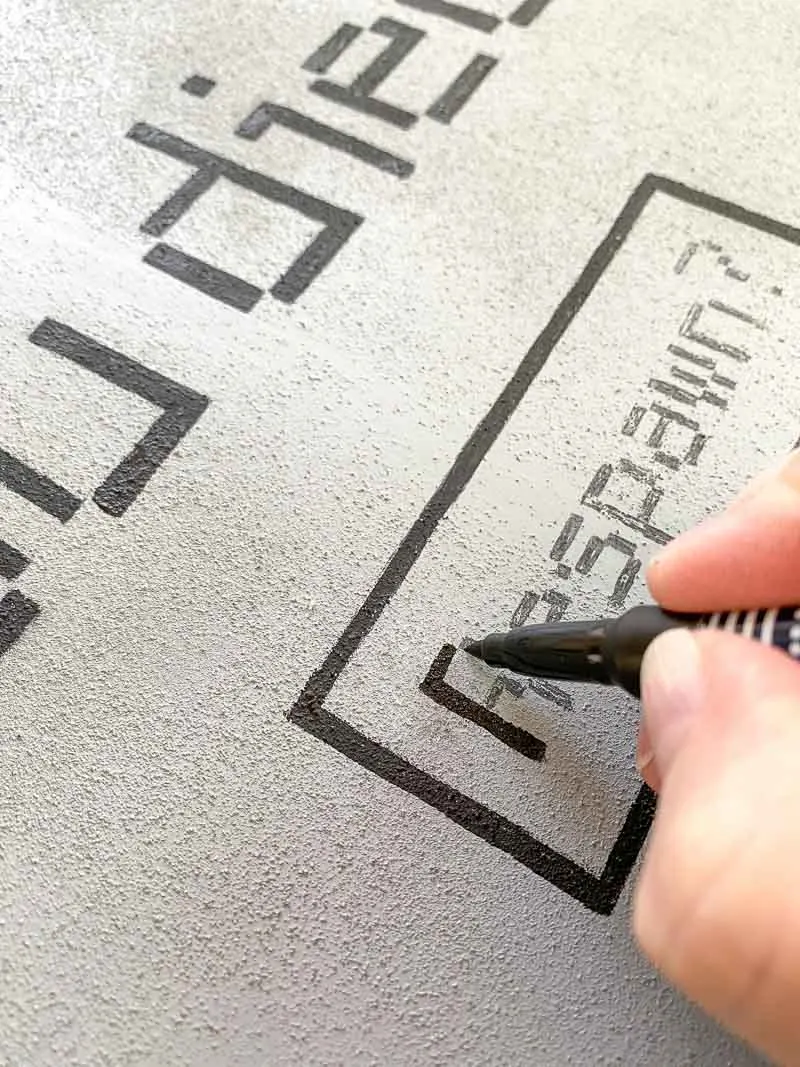 filling in the details of the DIY Halloween tombstones with a paint pen