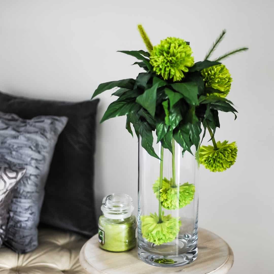 end table with flower arrangement and candle next to bed