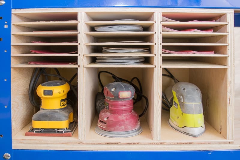 sanders and sandpaper organized in storage rack under workbench