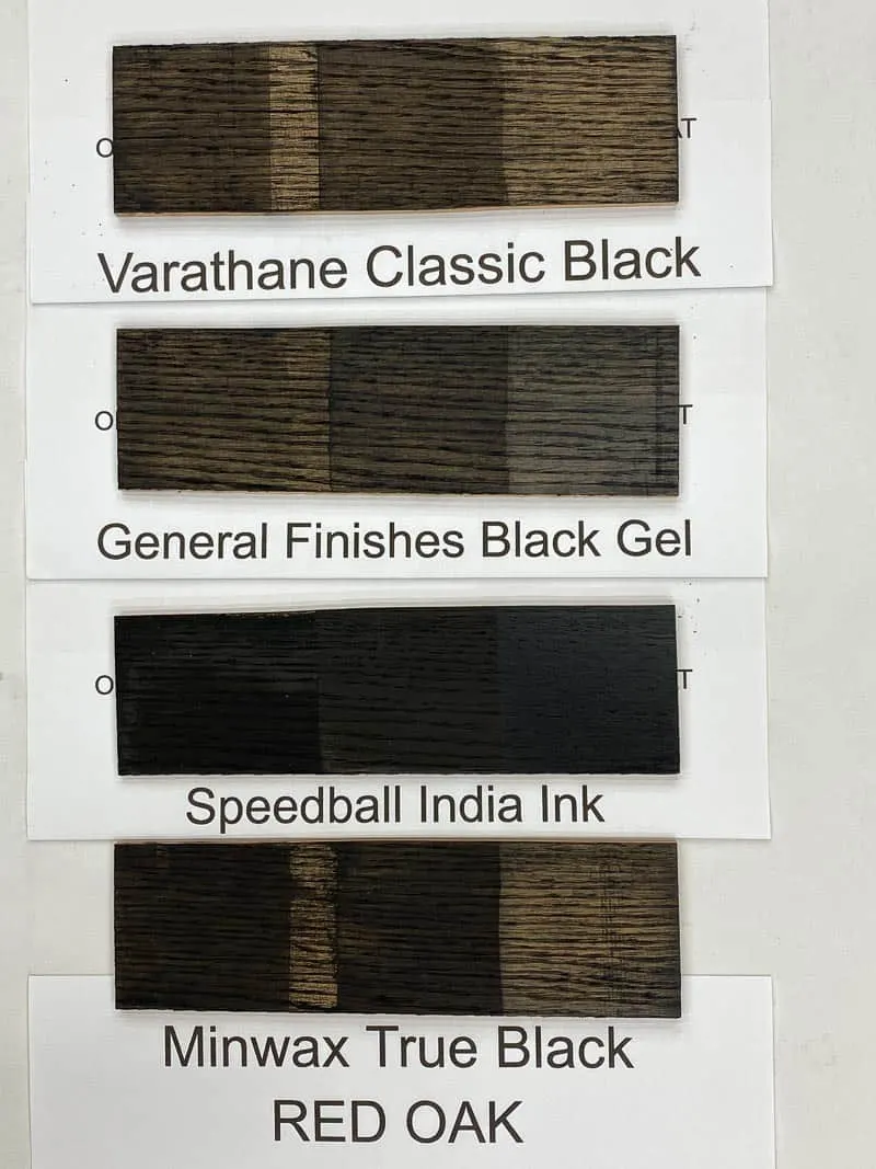 four black wood stain samples on red oak