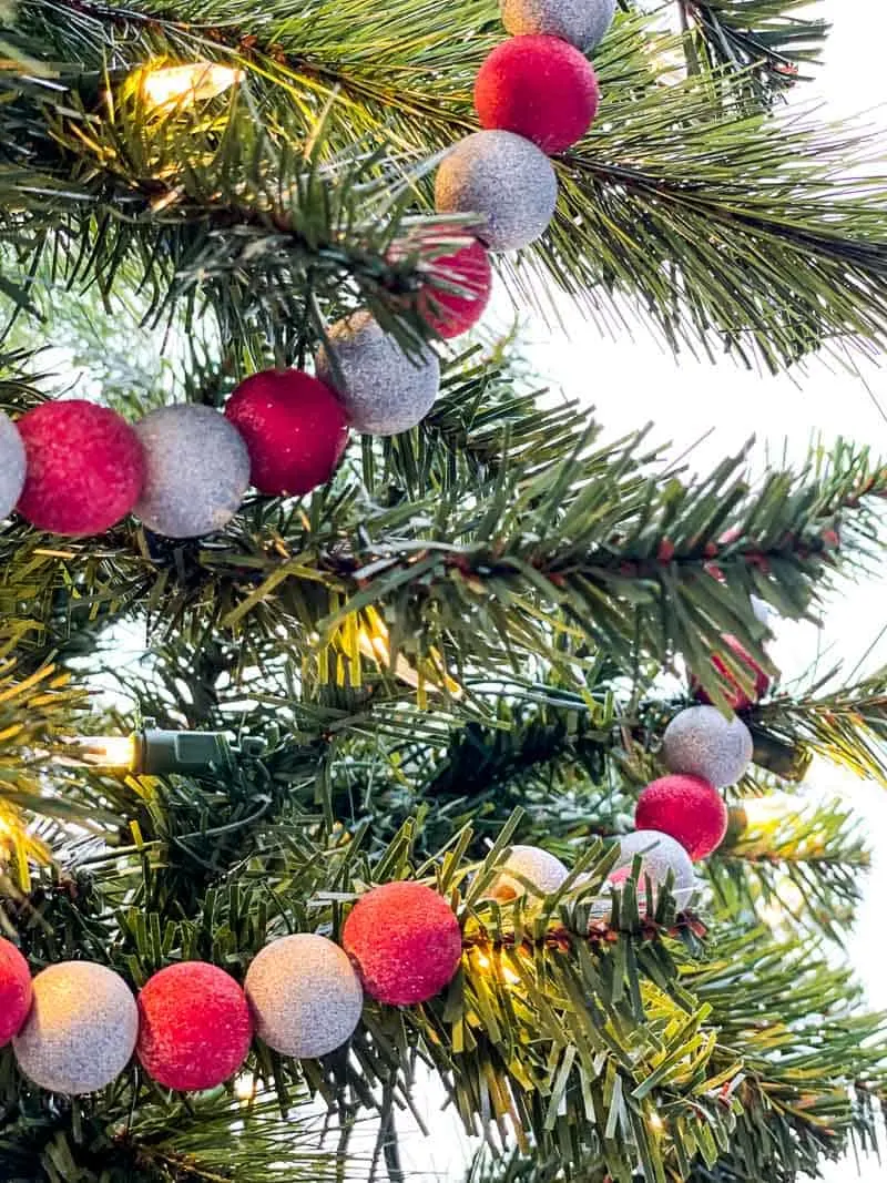 red and silver glitter spray paint on wooden bead garland in Christmas tree