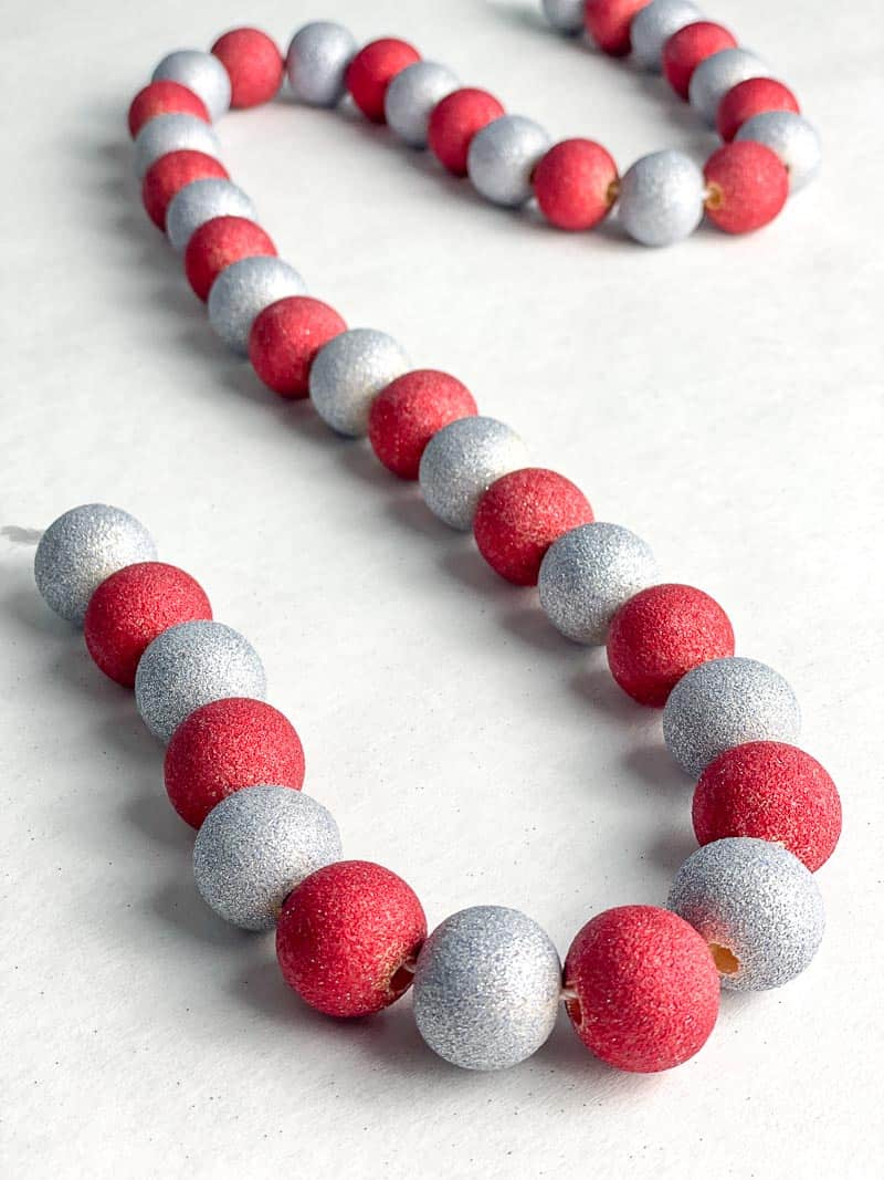 DIY wood bead garland painted with red and silver glitter spray paint