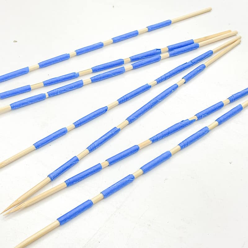 bamboo skewers with painters tape for holding wood beads in place
