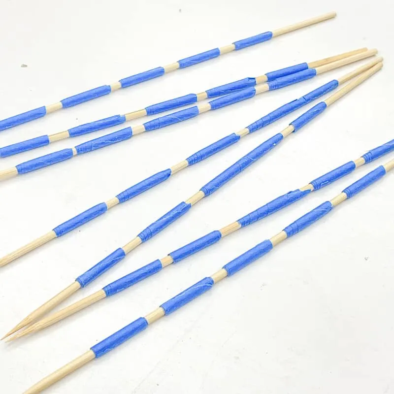 bamboo skewers with painters tape for holding wood beads in place