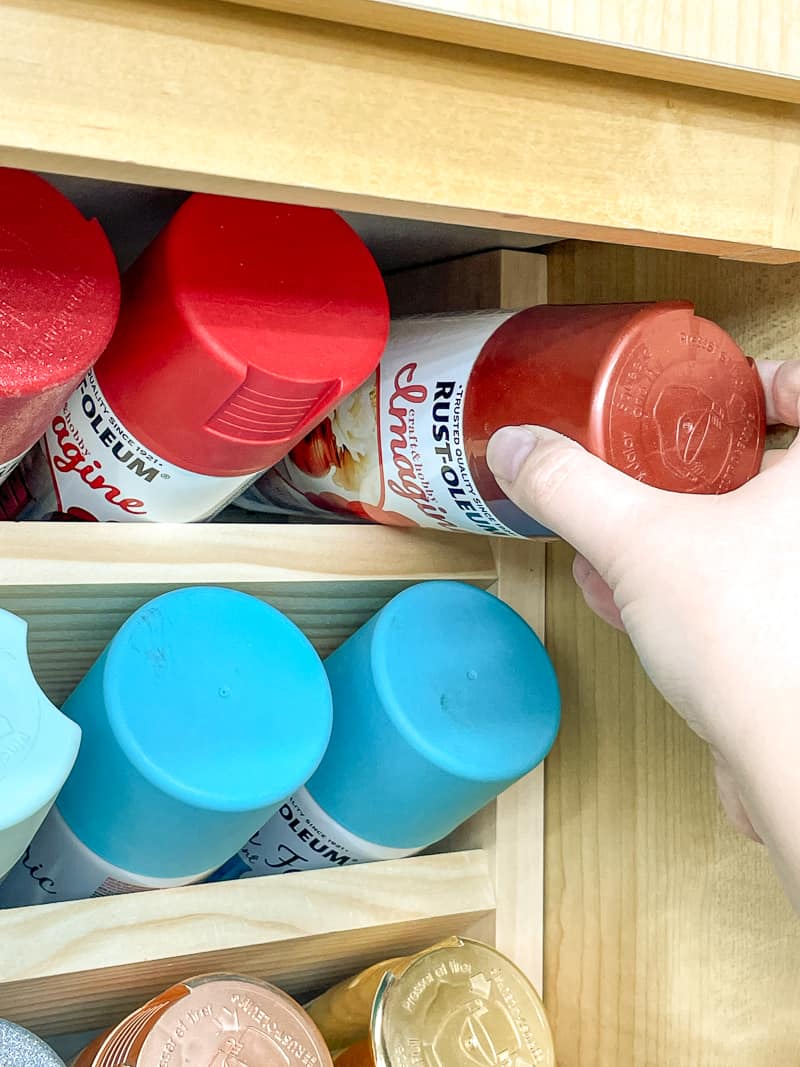 putting spray paint can on top shelf of spray paint storage rack