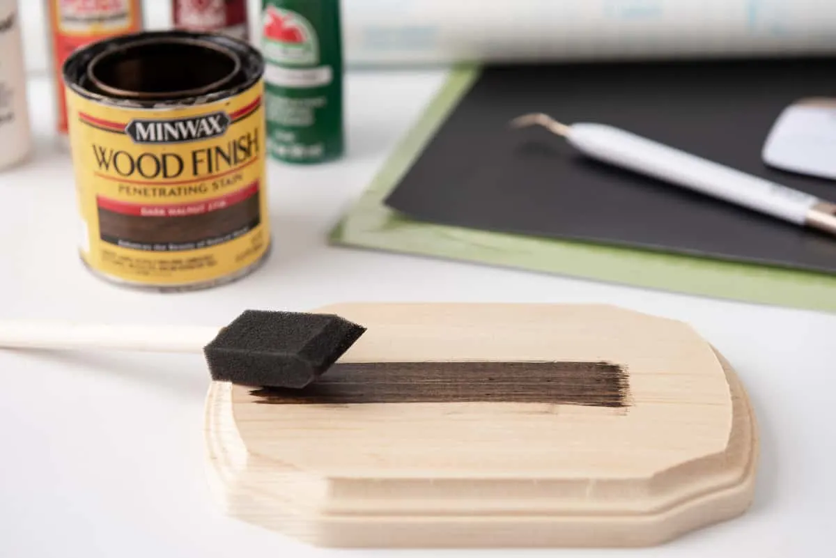 applying wood stain to plaque with a foam brush