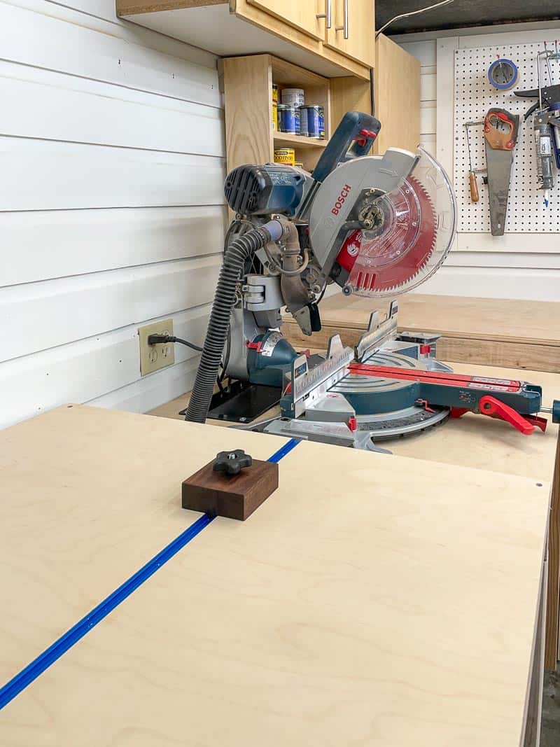 miter saw station with shelves and cabinets on the wall above