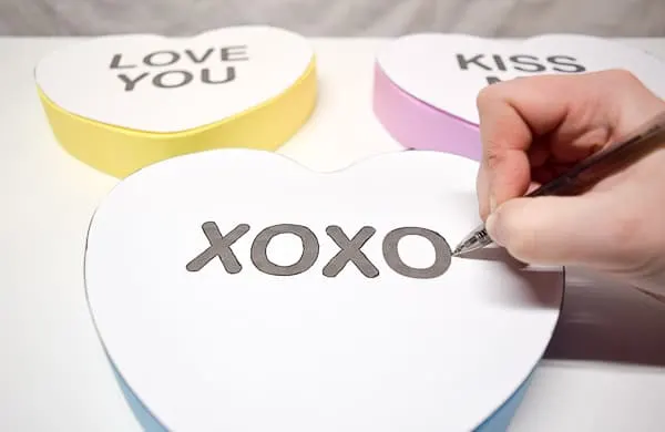 tracing lettering of conversation hearts onto the painted wood surface