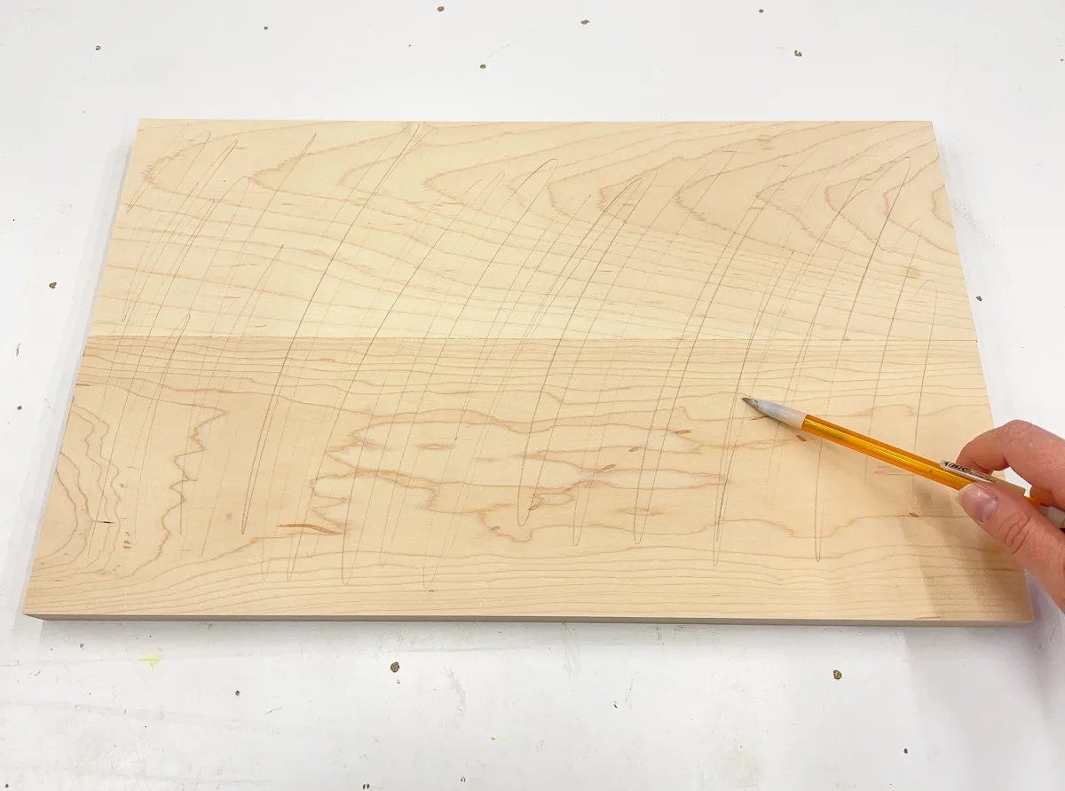 lightly drawing lines with a pencil over surface of the wood before sanding