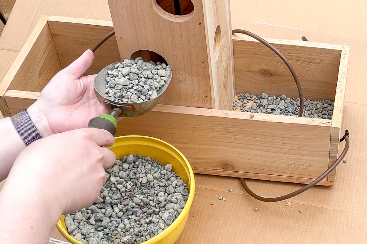 adding pea gravel to the bottom of a strawberry planter for drainage