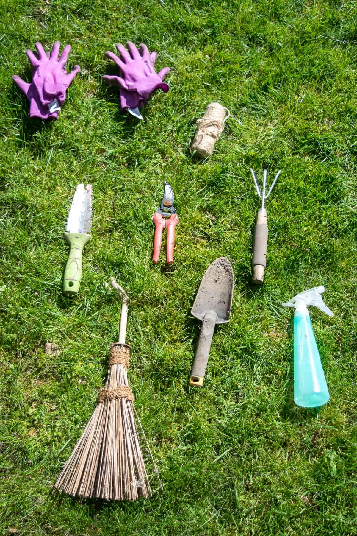 miscellaneous hand gardening tools laid out on grass