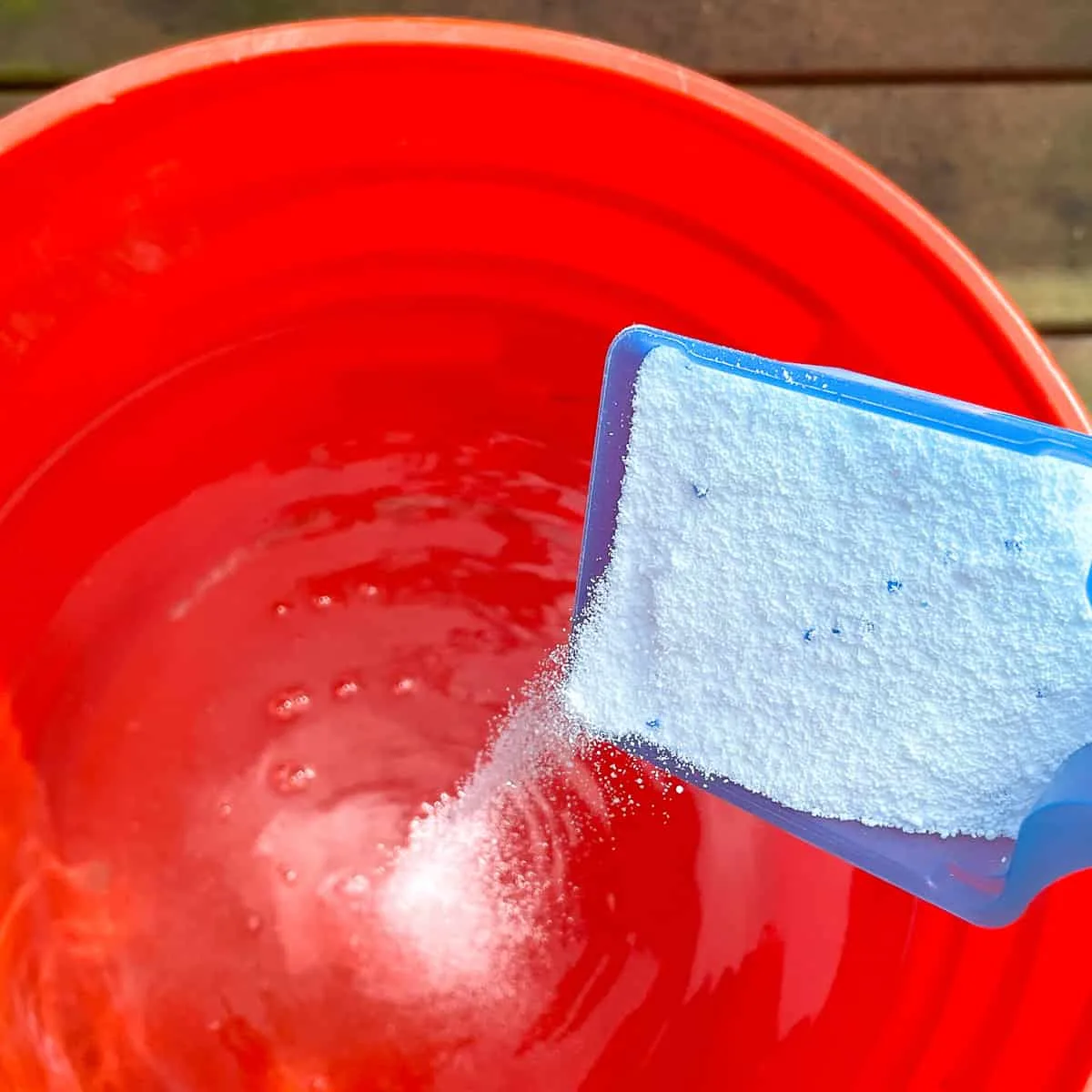 adding Oxiclean to warm water in orange bucket