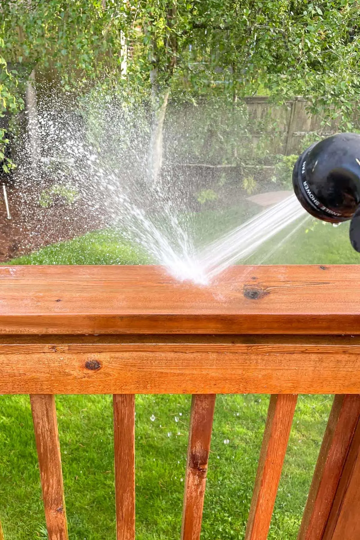 rinsing deck railing with a hose after applying cleaner