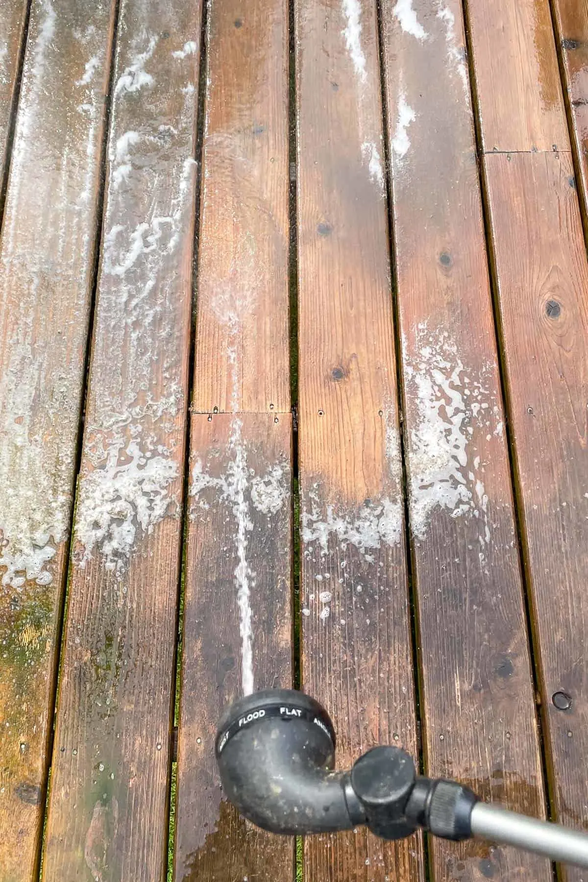 rinsing away deck cleaner and dirt with a hose